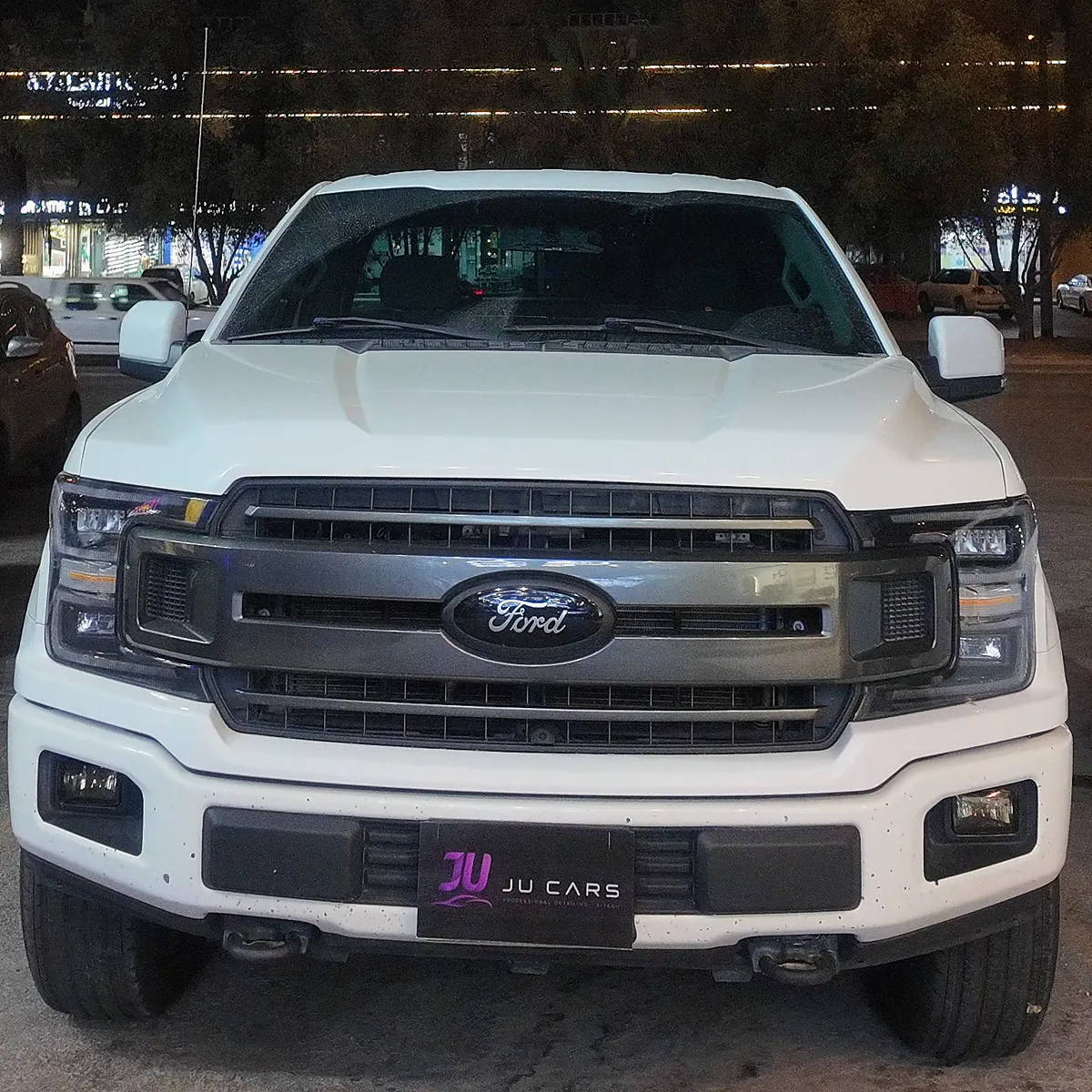 Whole front of a white Ford F-150 at night on arrival, before its color change to gloss black with PPF film at JU Riyadh Center